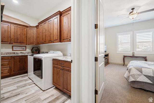 washroom with cabinets, washing machine and dryer, light colored carpet, and ceiling fan