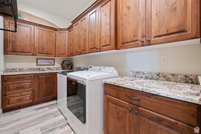 washroom featuring cabinets, washing machine and clothes dryer, and light hardwood / wood-style floors