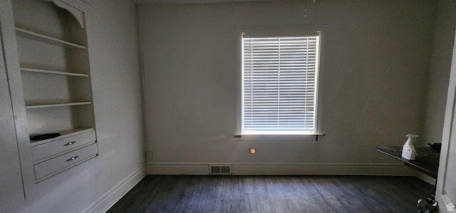 empty room featuring dark hardwood / wood-style flooring and built in shelves