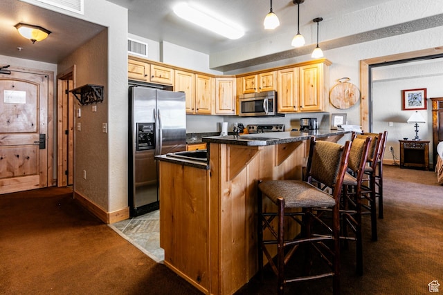2669 N Canyons Resort Dr W Unit 205, Park City, UT 84098 - kitchen with a peninsula, appliances with stainless steel finishes, dark colored carpet, dark countertops, and a kitchen bar