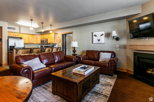 2669 N Canyons Resort Dr W Unit 205, Park City, UT 84098 - living room with a fireplace with raised hearth, dark carpet, visible vents, a textured ceiling, and baseboards