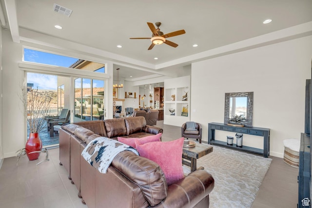 living room with built in features, ceiling fan with notable chandelier, visible vents, recessed lighting, and baseboards