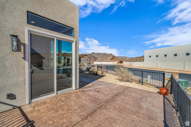 view of patio with a mountain view and fence