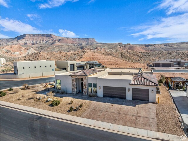 view of front of house with stucco siding, a mountain view, an attached garage, and a tile roof