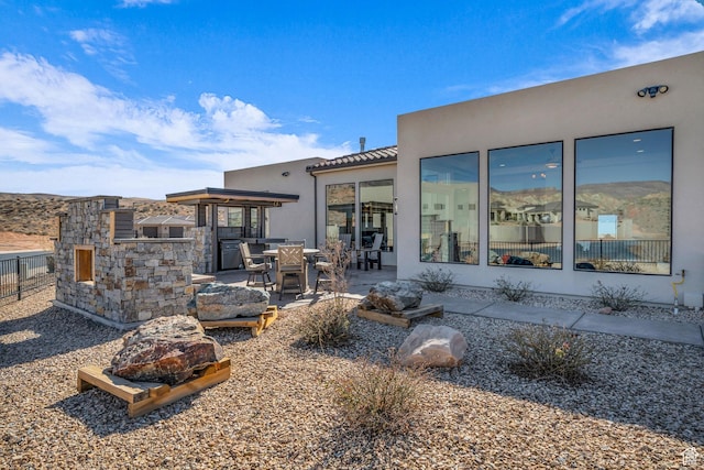 back of house with a patio, stucco siding, stone siding, a tile roof, and fence