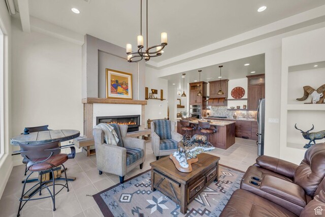 living area with a glass covered fireplace, recessed lighting, a chandelier, and light tile patterned flooring