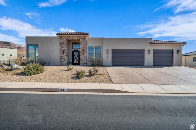 view of front of house with concrete driveway, stucco siding, a tiled roof, and an attached garage