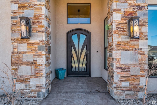 doorway to property featuring stucco siding and stone siding