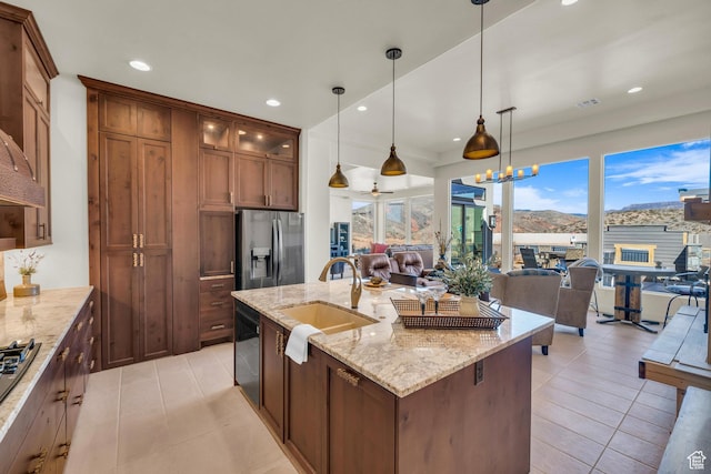 kitchen featuring light tile patterned floors, stainless steel fridge, dishwasher, a sink, and open floor plan