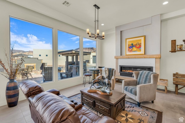 living area with visible vents, recessed lighting, a chandelier, and a glass covered fireplace