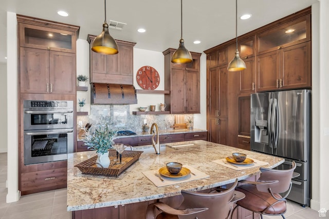kitchen with visible vents, a breakfast bar, light stone countertops, decorative backsplash, and stainless steel appliances