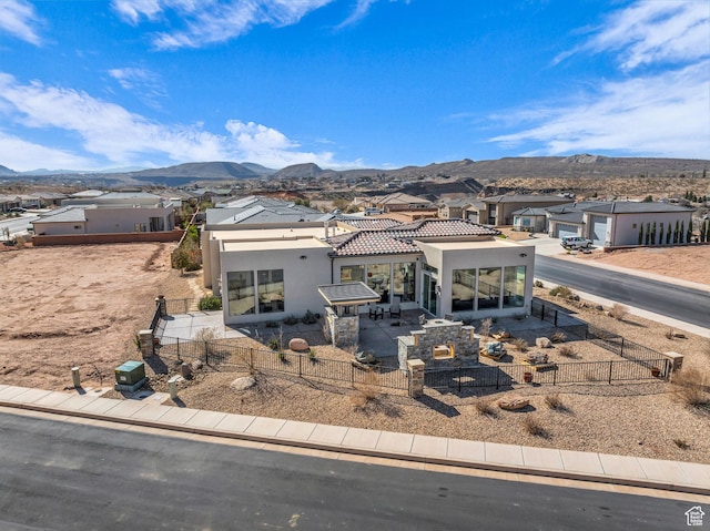 view of front of property with a mountain view, a patio, a fenced front yard, and a residential view