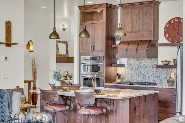 kitchen featuring light stone countertops, open shelves, stainless steel appliances, a center island with sink, and backsplash