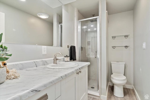 bathroom featuring vanity, hardwood / wood-style floors, an enclosed shower, and toilet