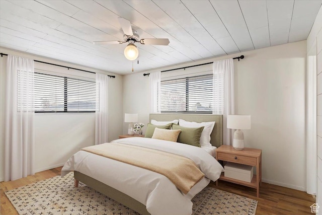 bedroom with multiple windows, wood-type flooring, and ceiling fan