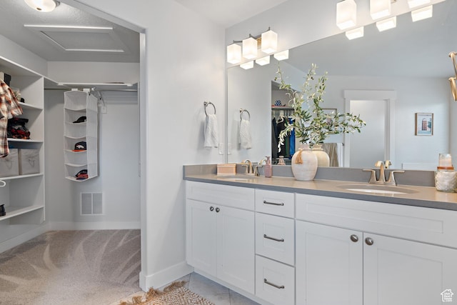 bathroom featuring double vanity, visible vents, a walk in closet, and a sink