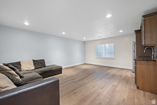 living area with light wood-style flooring, baseboards, and recessed lighting
