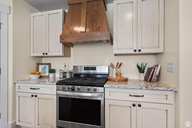kitchen featuring stainless steel gas range, light stone countertops, and premium range hood