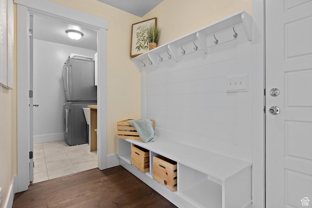 mudroom featuring stacked washer / dryer, baseboards, and dark wood finished floors