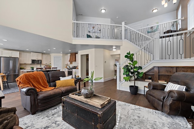 living area with recessed lighting, baseboards, stairs, wood finished floors, and a high ceiling