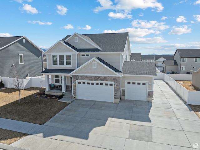 view of front of property featuring stone siding, concrete driveway, fence, and an attached garage