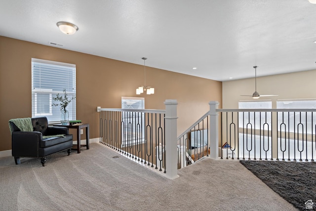 hall with a chandelier, carpet, plenty of natural light, and visible vents