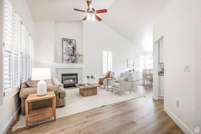 living room with ceiling fan, high vaulted ceiling, and light wood-type flooring