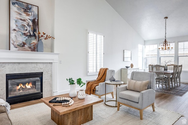 living room with lofted ceiling, a high end fireplace, wood-type flooring, and a healthy amount of sunlight