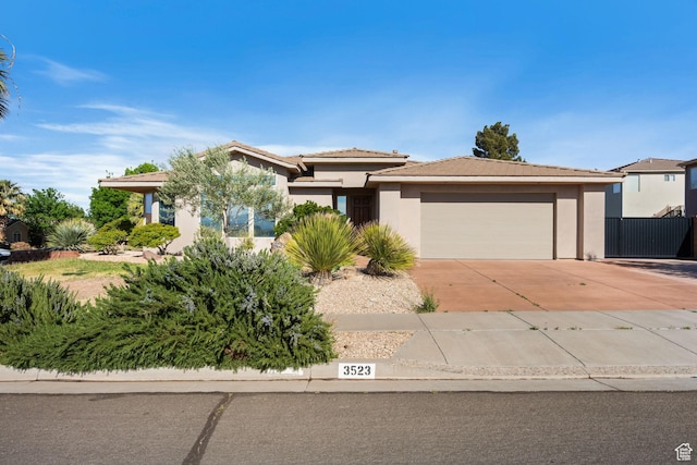 view of front facade with an attached garage, a tile roof, fence, stucco siding, and driveway