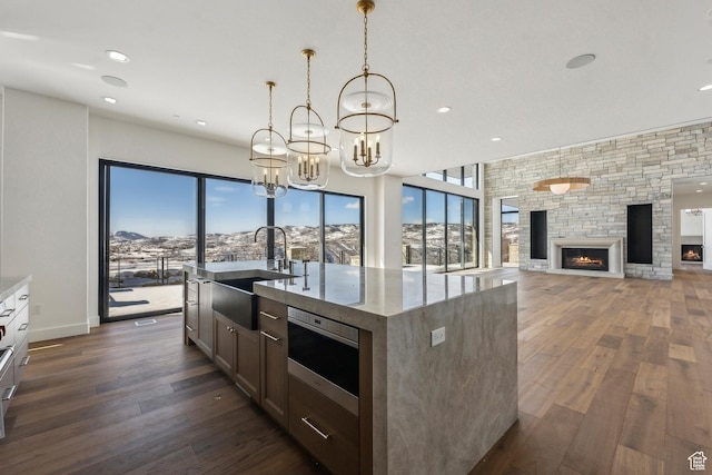 2738 Longspur Ln, Park City, UT 84098 - kitchen with pendant lighting, sink, a kitchen island with sink, a fireplace, and light stone countertops
