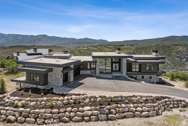 2738 Longspur Ln, Park City, UT 84098 - back of house featuring a chimney, a mountain view, stone siding, and an attached garage
