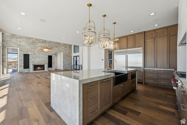 2738 Longspur Ln, Park City, UT 84098 - kitchen featuring pendant lighting, sink, a fireplace, an island with sink, and dark hardwood / wood-style flooring