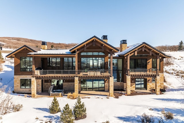 9791 N Uinta Dr, Kamas, UT 84036 - snow covered house with stone siding, a patio, a balcony, and a chimney