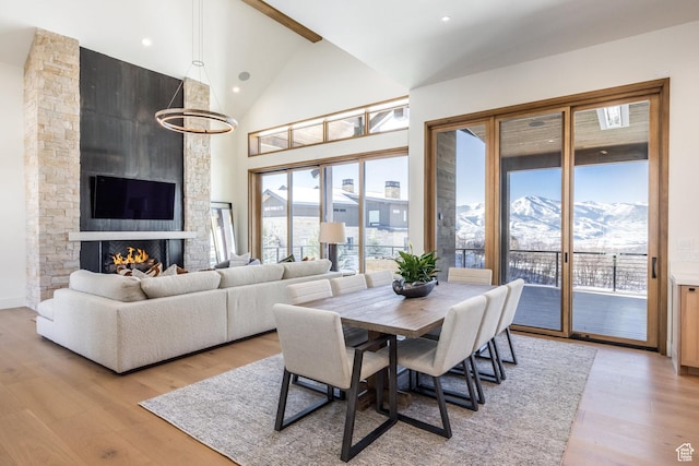 9791 N Uinta Dr, Kamas, UT 84036 - dining space featuring high vaulted ceiling, a large fireplace, light wood-style floors, a mountain view, and an inviting chandelier