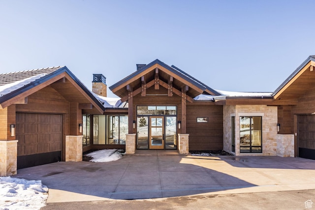 9791 N Uinta Dr, Kamas, UT 84036 - view of front facade with stone siding, a chimney, a garage, driveway, and french doors