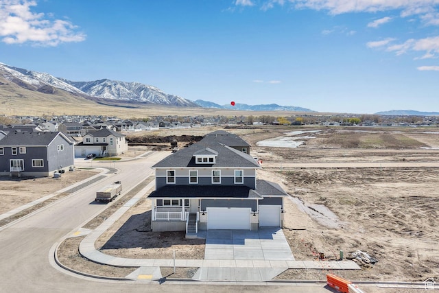 view of front facade with a residential view, driveway, a mountain view, and an attached garage