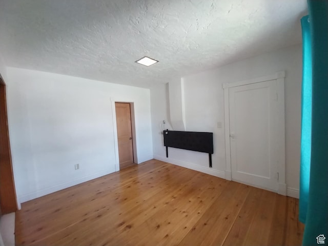 unfurnished living room featuring hardwood / wood-style flooring, baseboards, and a textured ceiling