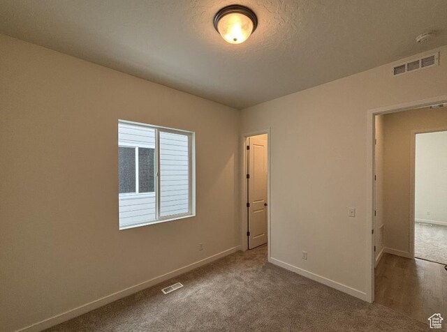 283 E Polaris Dr Unit 102, Saratoga Springs, UT 84045 - unfurnished bedroom featuring visible vents, a textured ceiling, carpet, and baseboards