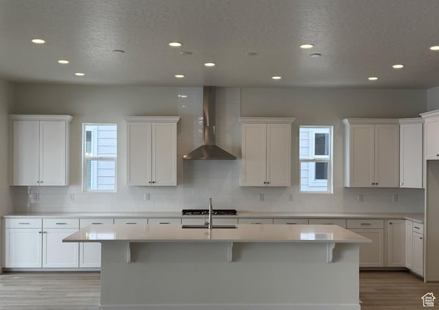 283 E Polaris Dr Unit 102, Saratoga Springs, UT 84045 - kitchen featuring a center island with sink, plenty of natural light, wall chimney exhaust hood, and light wood finished floors