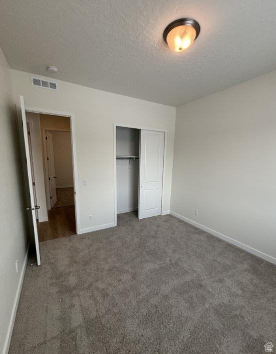 283 E Polaris Dr Unit 102, Saratoga Springs, UT 84045 - unfurnished bedroom featuring carpet, visible vents, baseboards, a closet, and a textured ceiling