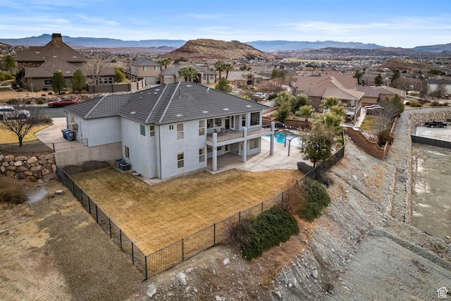 rear view of property with central AC unit, a yard, a fenced in pool, a balcony, and a mountain view