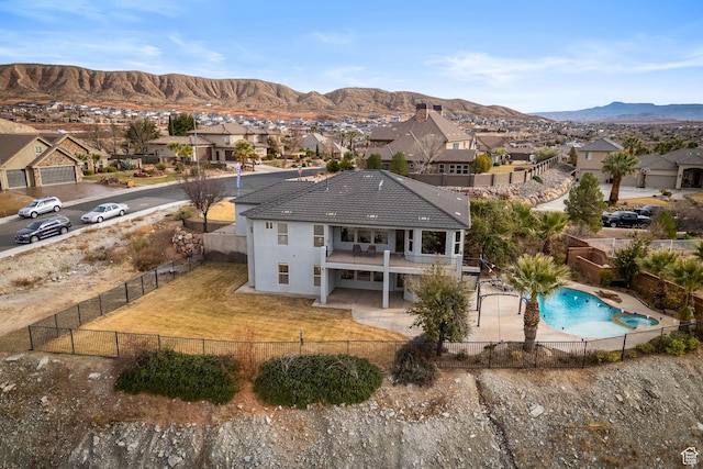 rear view of house featuring a patio area, a fenced in pool, a balcony, and a mountain view