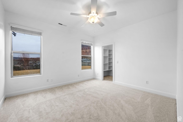 unfurnished bedroom with ceiling fan, a closet, light colored carpet, and a spacious closet