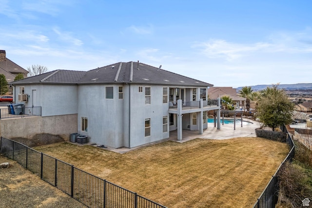 back of house with a fenced in pool, a lawn, a patio area, and a balcony