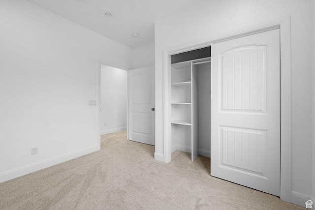 unfurnished bedroom with light carpet and a closet
