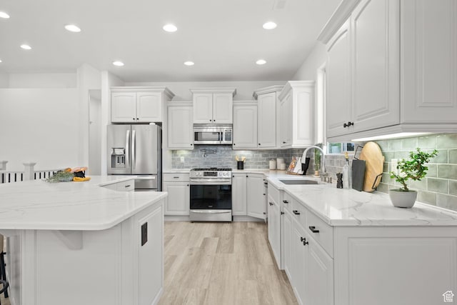 kitchen with appliances with stainless steel finishes, a breakfast bar, a center island, sink, and white cabinetry