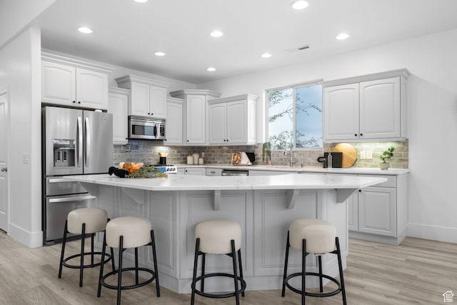 kitchen featuring a center island, appliances with stainless steel finishes, white cabinetry, and a kitchen bar