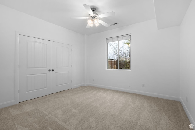 unfurnished bedroom featuring light carpet, a closet, and ceiling fan