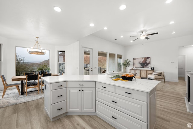 kitchen featuring hanging light fixtures, a center island, white cabinetry, and light hardwood / wood-style flooring