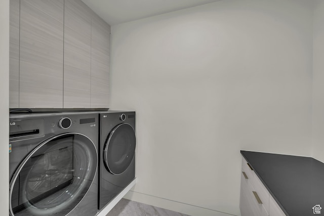 laundry room featuring separate washer and dryer and cabinets
